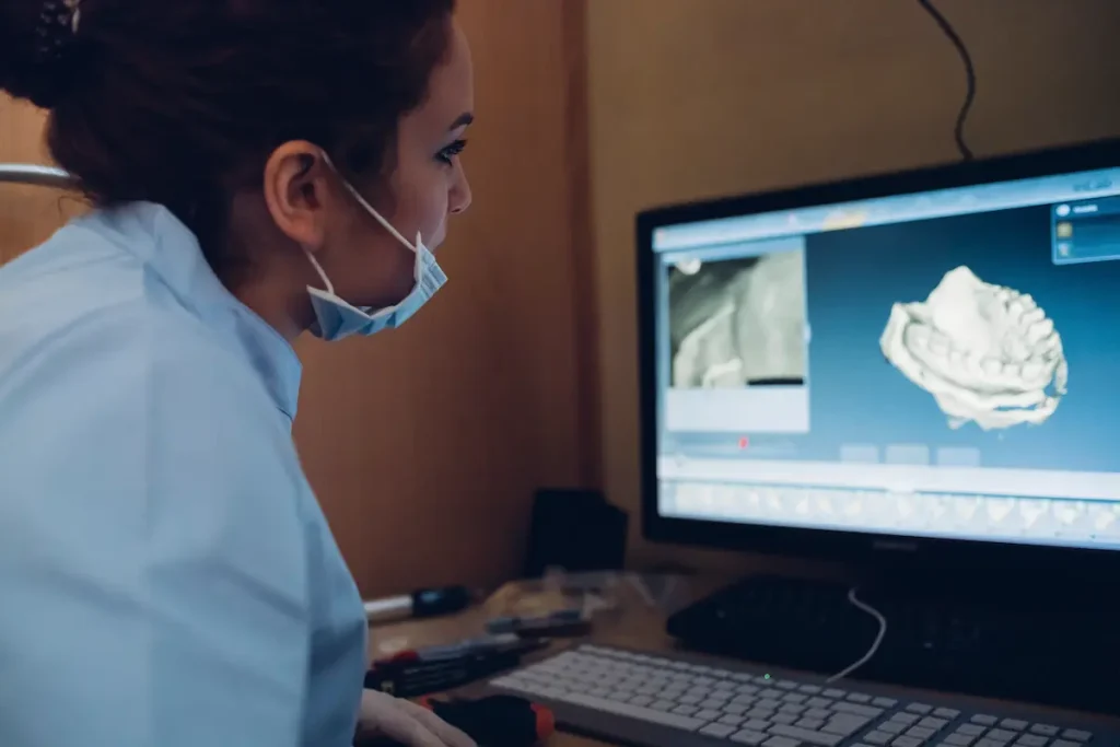 A dentist looking at a computer screen with dental records