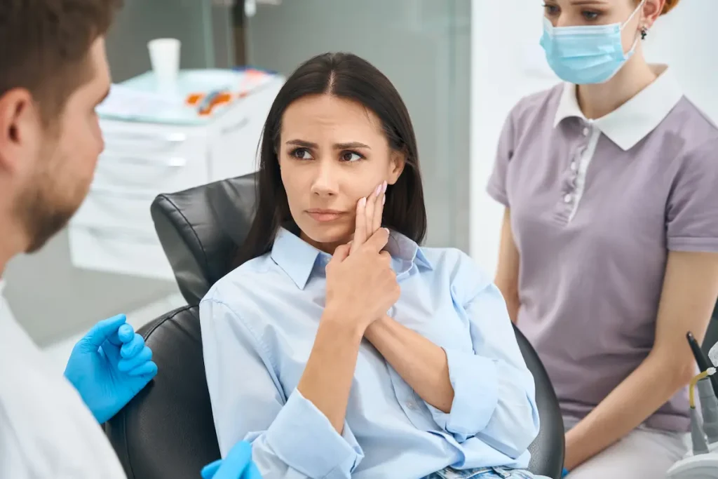 A person holding their face speaking to a dentist